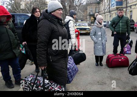 ODESA, UKRAINE - 10. MÄRZ 2022 - Menschen, die vor der russischen Invasion fliehen, halten ihre Habseligkeiten in der Hand, da kostenlose Evakuierungsbusse sie zum Bord bringen sollen Stockfoto