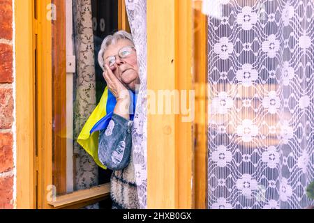 Ältere Frau mit der Ukraine die Fahne weinend, leidend und bete Frieden während des Kriegskonflikts zwischen Russland und der Ukraine, Invasion von Russland in der Ukraine Stockfoto