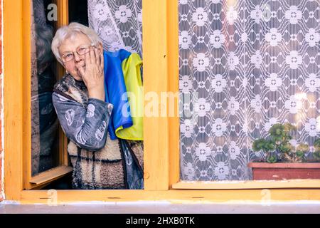 Ältere Frau mit ukrainischer Flagge weint, leidet und betet während des Kriegskonflikts zwischen Russland und der Ukraine, Invasion Russlands in der Ukraine, betet Stockfoto