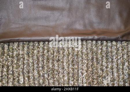 Textur aus schwarzem Leder und gestricktem Wollschal, horizontales Format Stockfoto