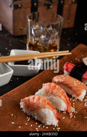 Frisches Sushi-Sortiment auf rustikalem Holzteller Stockfoto
