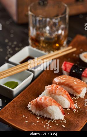 Frisches Sushi-Sortiment auf rustikalem Holzteller Stockfoto