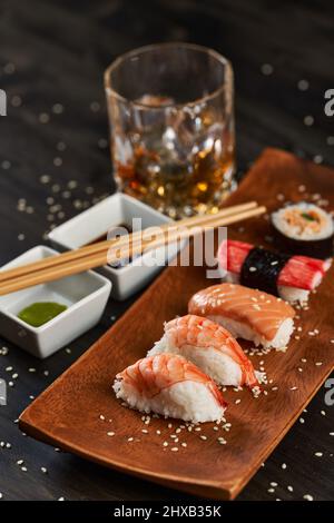 Frisches Sushi-Sortiment auf rustikalem Holzteller Stockfoto