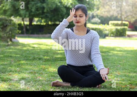 Mädchen üben anulom vilom Yoga im Park. Stockfoto