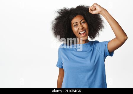 Enthusiastische afroamerikanische Frau jubelt, geballte Faust zur Unterstützung aufwirft, protestiert, die Menschenrechte bekämpft, jubelt oder wurzelt, steht über Stockfoto