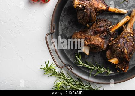 Lammschenkel in einem reichhaltigen Soße-Set, auf weißem Steintisch-Hintergrund, Draufsicht flach liegend, mit Platz für Text Stockfoto