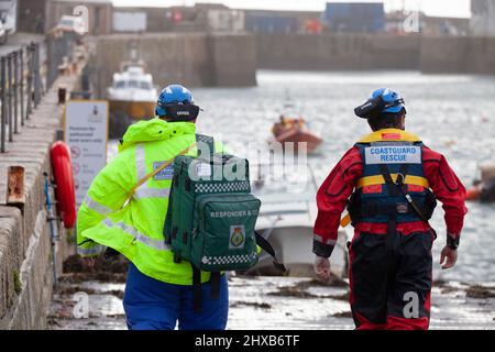 Rettungskräfte treffen sich mit dem Küstenrettungsboot, um einen Unfall zu überprüfen, der während eines Sturms in Cornwall aus dem Wasser gezogen wurde. Erste-Hilfe-RNLIR Stockfoto