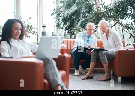 In der Bürolobby grüßen sich Geschäftsmann und Geschäftsfrau gegenseitig mit den Händen. Stockfoto