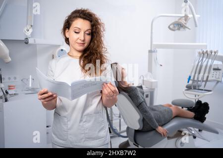 Porträt einer Zahnärztin in einer Klinik. Zahnklinik und Mundgesundheitskonzept. Der Arzt prüft die Karte des Kunden. Kopierraum. Stockfoto