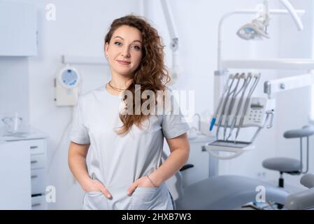 Hochqualifizierte weibliche Zahnärztin posiert in der Klinik über modernen Büro, leeren Raum. Stockfoto