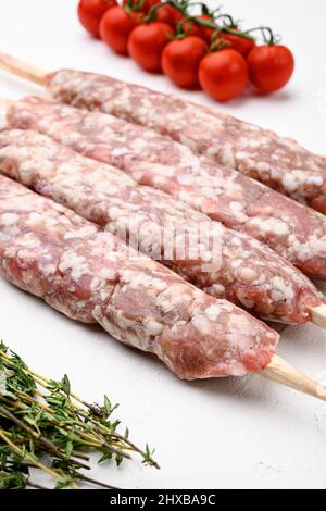 Hackfleisch und geformte Lamm Hammelfleisch Kebabs Set, mit Grillzutaten, auf weißem Steintisch Hintergrund Stockfoto