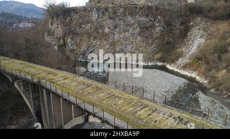 Seitenansicht einer alten verlassenen Brücke auf einem Hintergrund von Bergen in dem kleinen Dorf in der Spätherbst-Saison. Aufnahme. Luftaufnahme von moosigen Steinbrücke und Stockfoto