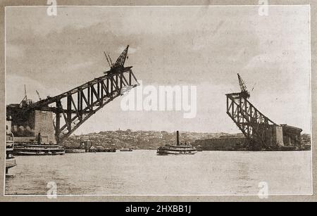 Ein frühes Bild einer Hafenfähre von Sydney unter der Sydney Harbour Bridge, die noch im Bau ist. Stockfoto