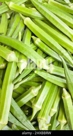 Okra oder Okro, auch bekannt als Ladies' Fingers, pflanzlicher Hintergrund, Nahaufnahme in geringer Schärfentiefe Stockfoto