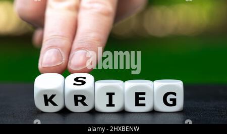 Hand dreht Würfel und ändert das deutsche Wort 'Krieg' in 'Sieg'. Stockfoto