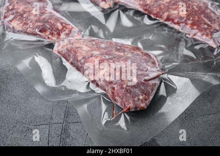 Beef-Patties in einer Vakuumverpackung, auf grauem Steintisch-Hintergrund, mit Platz für Text Stockfoto