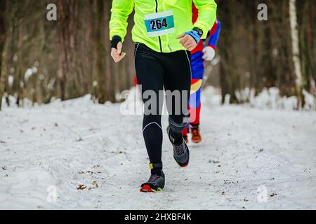 Gruppenläufer Athleten laufen Schneeliste im Wald Stockfoto