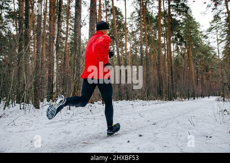 Männlicher Läufer beim Winterrennen im Wald Stockfoto