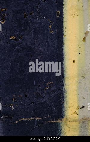 Alte schwarze gelbe Farbe mit Rissen an der Wand als Hintergrund, Textur, selektiver Fokus Stockfoto