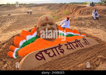 Pushkar, Rajasthan, Indien. 10. März 2022. Der Sandkünstler Ajay Rawat entwirft eine Skulptur des Uttar Pradesh-Chefs Yogi Adityanath, um ihm zu seinem Sieg in DEN UMFRAGEN DER Versammlung zu gratulieren. Die Bharatiya Janata Party (BJP) gewinnt bei den Parlamentswahlen in den Bundesstaaten Uttar Pradesh, Uttarakhand, Goa und Manipur. (Bild: © Sumit Sarawat/Pacific Press via ZUMA Press Wire) Stockfoto