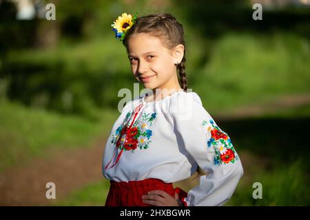 Ein kleines ukrainisches und weißrussisches Mädchen in einem bestickten Hemd auf einem Sommerhintergrund. Stockfoto