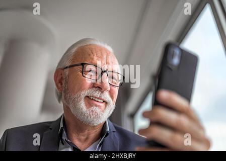 Nahaufnahme aus dem niedrigen Winkel Porträt eines Geschäftsmannes Unternehmer Manager mit Mobiltelefon-Smartphone in modernen hellen Büro überprüfen Stockfoto
