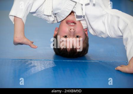 Ein kleiner Junge in einem Kimano auf dem Kopf. Das Kind ist mit Judo oder Karate beschäftigt. Abschnitt für Kinder des Kampfsports. Stockfoto