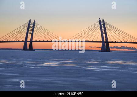 Die Silhouette der Seilbrücke über die Schiffsfahrbahn auf dem Western High-Speed ​ ​ Diameter vor dem Hintergrund des Sonnenuntergangs im Dezember. Stockfoto