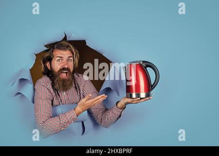 Kerl mit Bart trinken Tee. Brutal kaukasischen Hipster mit Wasserkocher. Trinken Sie heißes Getränk. Gute Qualität. Überrascht Shop-Assistent. Reifer Mann Stockfoto