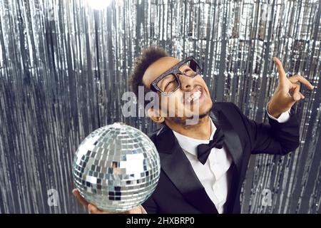Glücklich lustige junge schwarze Kerl in Smoking und Brille tanzen und Spaß auf der Party Stockfoto
