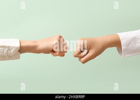 Hände von Frauen mit geballten Fäusten auf farbigem Hintergrund Stockfoto