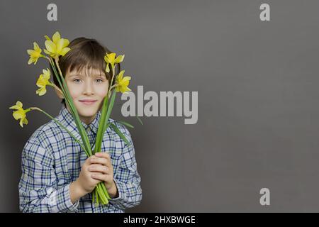 Narcissus - ein Blumenstrauß in der Hand, Blumen Gelber Narzissen Frühlingsblumen Narzissen, Nahaufnahme isoliert auf grauem Hintergrund, Junge mit Blumen, Stockfoto