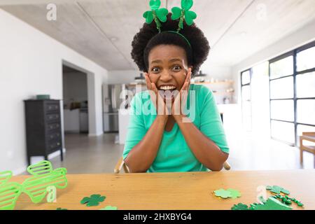 Porträt einer überraschten afroamerikanischen Frau mit mittlerem Erwachsenen im Schamrock-Haarreif zu Hause Stockfoto