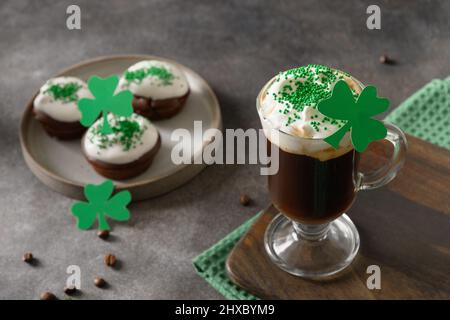 Irischer Kaffee und Cupcakes für den St. Patricks Day auf grauem Hintergrund. Nahaufnahme. Stockfoto