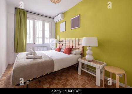 Schlafzimmer mit Boxspring und King-Size-Matratze in der Ferienwohnung mit Eichenparkett-Boden mit Palette Kopfteil und Pistazien grün painte Stockfoto