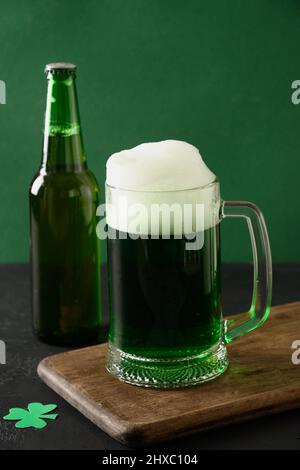 Patrick's Day traditionelles grünes Bier und Flasche auf grünem Hintergrund. Vertikales Format. Nahaufnahme. Stockfoto