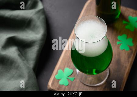 Patrick's Day traditionelles Bier auf Holzbrett auf schwarzem Hintergrund. Nahaufnahme. Shamrock Symbol des Glücks. Stockfoto