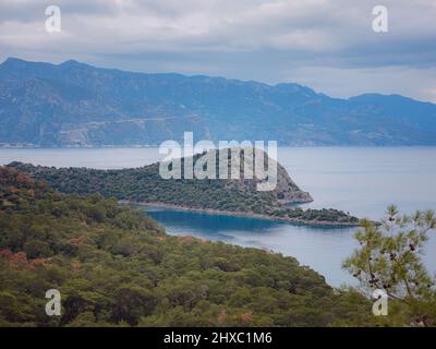 Reise zur Lagune in Oludeniz, Fethiye, Türkei. Strand in der Nähe von Darbogaz. Mit Blick auf den Berg Babadag, Winterlandschaft mit Bergen, grüner Wald, azurblaues Wasser Stockfoto