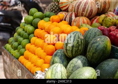 Frisch und lokal. Gestapelte Reihen von frischem Obst - Limetten, Orangen und Melonen - auf einem indischen Markt. Stockfoto