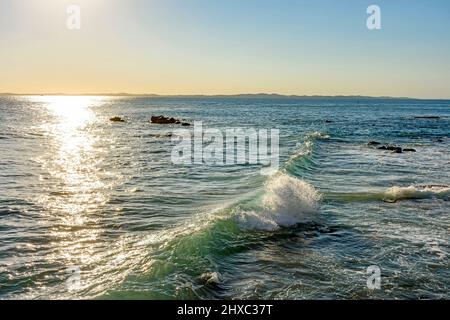 Sonnenuntergang über dem Wasser des Meeres in der Stadt Salvador in Bahia mit kleinen Wellen, die entlang der Felsen brechen Stockfoto