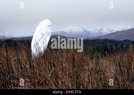 Ein gruseliger Geist in einem Laken. Wandern über einen Berg an einem Wintertag. Schottland. VEREINIGTES KÖNIGREICH Stockfoto