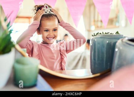 Denken Sie immer daran, dass Sie eine Prinzessin. Aufnahme eines kleinen Mädchens, das zu Hause eine Krone im Spiegel aufsetzt. Stockfoto