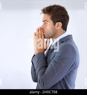 Betet für diese Förderung. Profil eines Geschäftsmannes, der mit Handflächen zusammen stand und sich als Geste der Vorfreude gegen seinen Mund ruhte. Stockfoto
