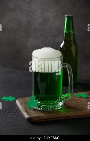 Patrick's Day traditionelles grünes Bier und Flasche auf schwarzem Hintergrund. Vertikales Format. Stockfoto