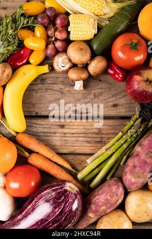 Direkt über Schuss von verschiedenen Gemüse und Früchten mit leerer Herzform auf Holztisch gemacht Stockfoto