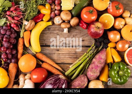 Ansicht von verschiedenen Gemüse und Früchten mit leerer Herzform auf Holztisch Stockfoto