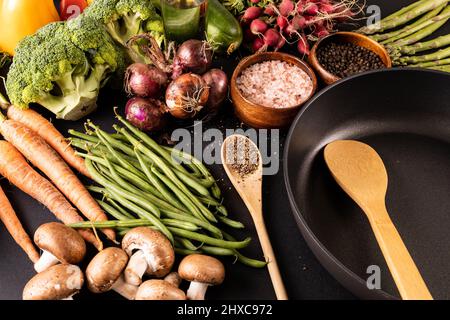 Bratpfanne mit Gewürzen und verschiedenen Gemüse- und Ölflaschen auf dem Tisch Stockfoto