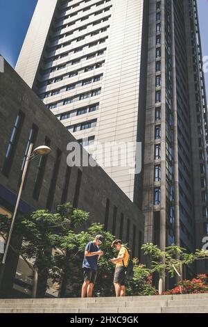 Jugendliche konsultieren die Karte auf dem Smartphone. Lächelnde Teenager glücklich in der Stadt. Jungs genießen Urlaub, Wolkenkratzer, Metropole, entdecken Sie neues Land. Jugend, ge Stockfoto