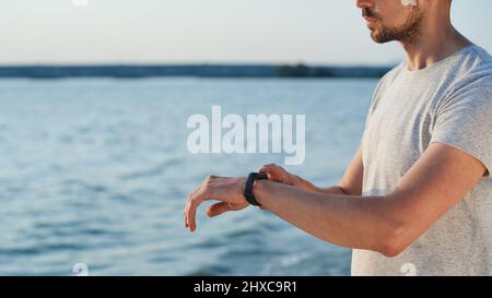 Sportlicher Mann mit einer smarten Fitnessuhr, die am Meer steht. Stockfoto