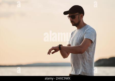 Sportlicher Mann, der seine smarte Fitnessuhr anschaut. Stockfoto